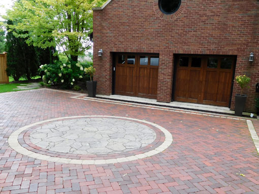 The driveway ends at the next-door neighbor's garage. Note the round shape of the window is repeated in the circular inset in the driveway.