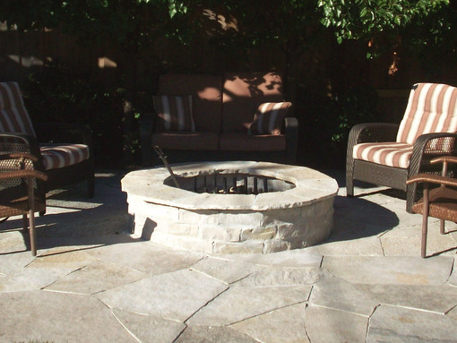 A mortared stone fire pit with limestone coping is integrated into a crazy quilt limestone patio.