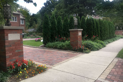 Mortared brick columns along the street are topped with ornate lanterns that match the home's fixtures. An Arborvitae hedge adds privacy to the front yard.