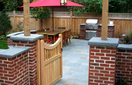 Cedar arbor and gate with mortared brick pillars leading to bluestone patio