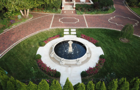 Formal fountain with hedge surrounded by paver driveway