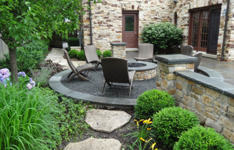 Gravel firepit area with natural stone firepit, walls, and pillars