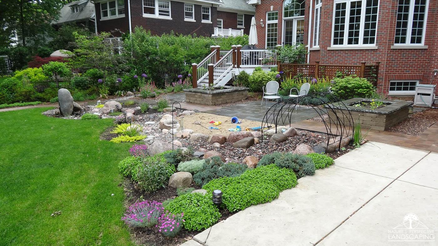 boulder water feature, sand play area, play tunnel and perennials-Nature's Perspective Landscaping