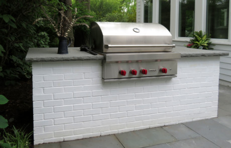 painted brick built-in grill on a bluestone patio