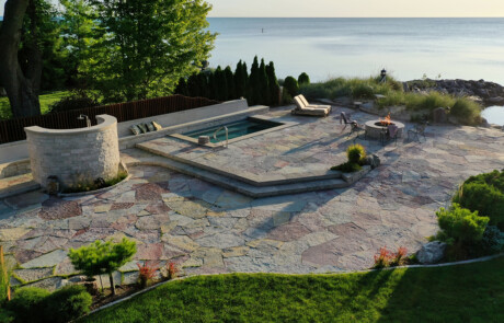 Lakeside stone patio with pool, firepit, and outdoor shower