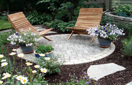 Small circular paver patio with seating and annuals