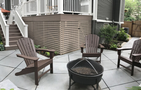 Diamond patterned patio with deck and chairs around a firepit