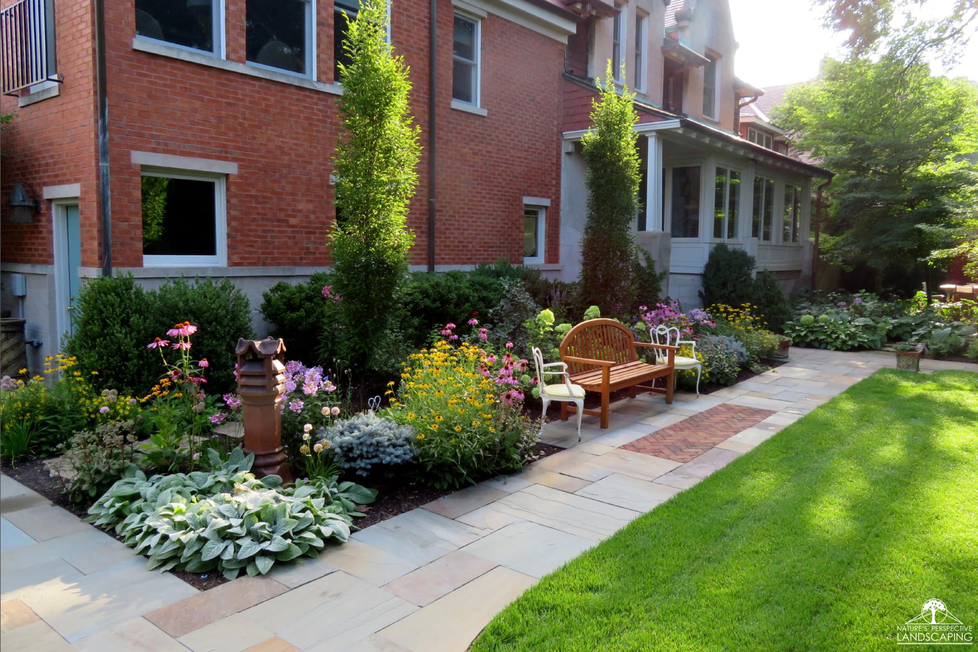 bench sitting area inside sunny perennial border planting