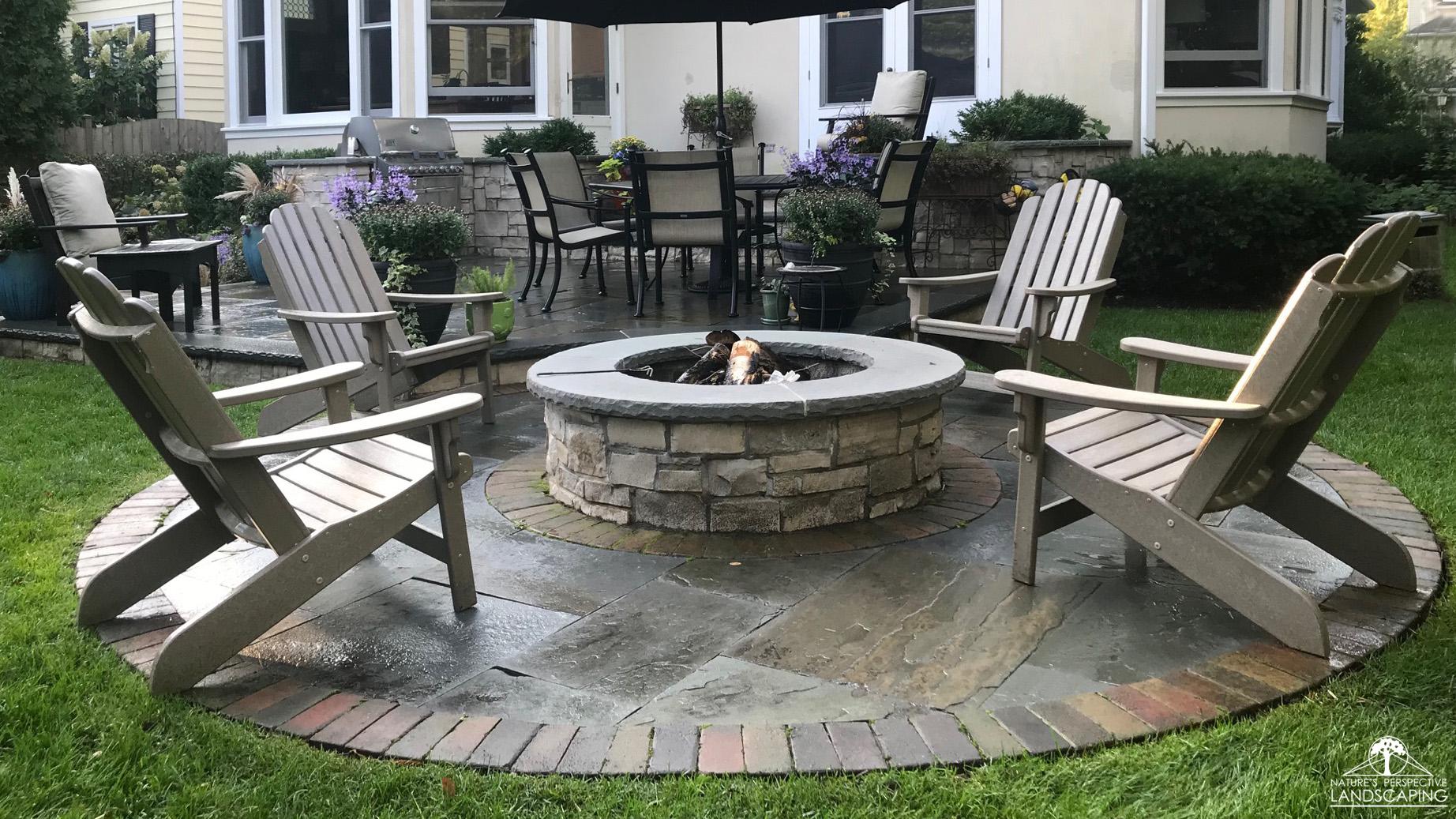 mortared limestone fire pit on a round bluestone and clay paver patio