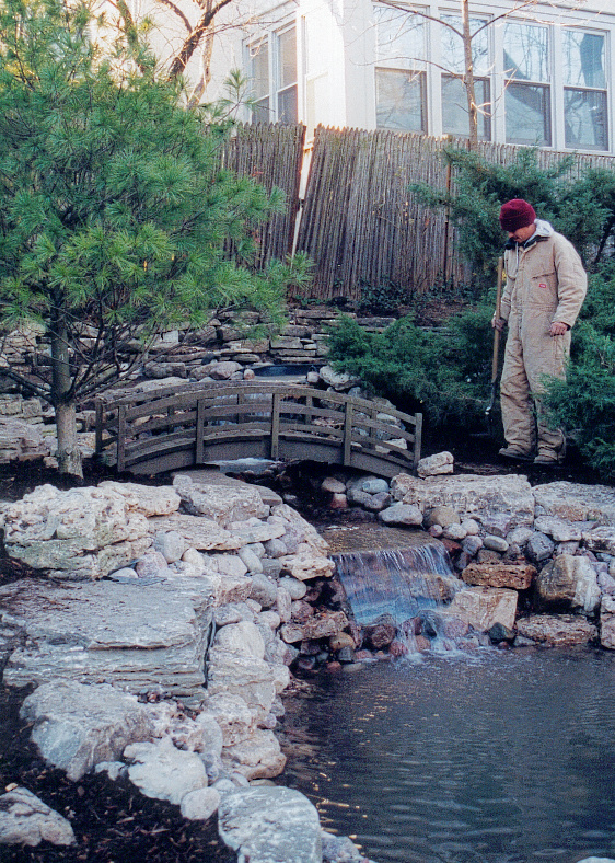 supervisor cleaning Japanese bridge with waterfall and pond