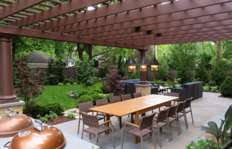 lush backyard with plantings, large fiberglass pergola and bluestone patio