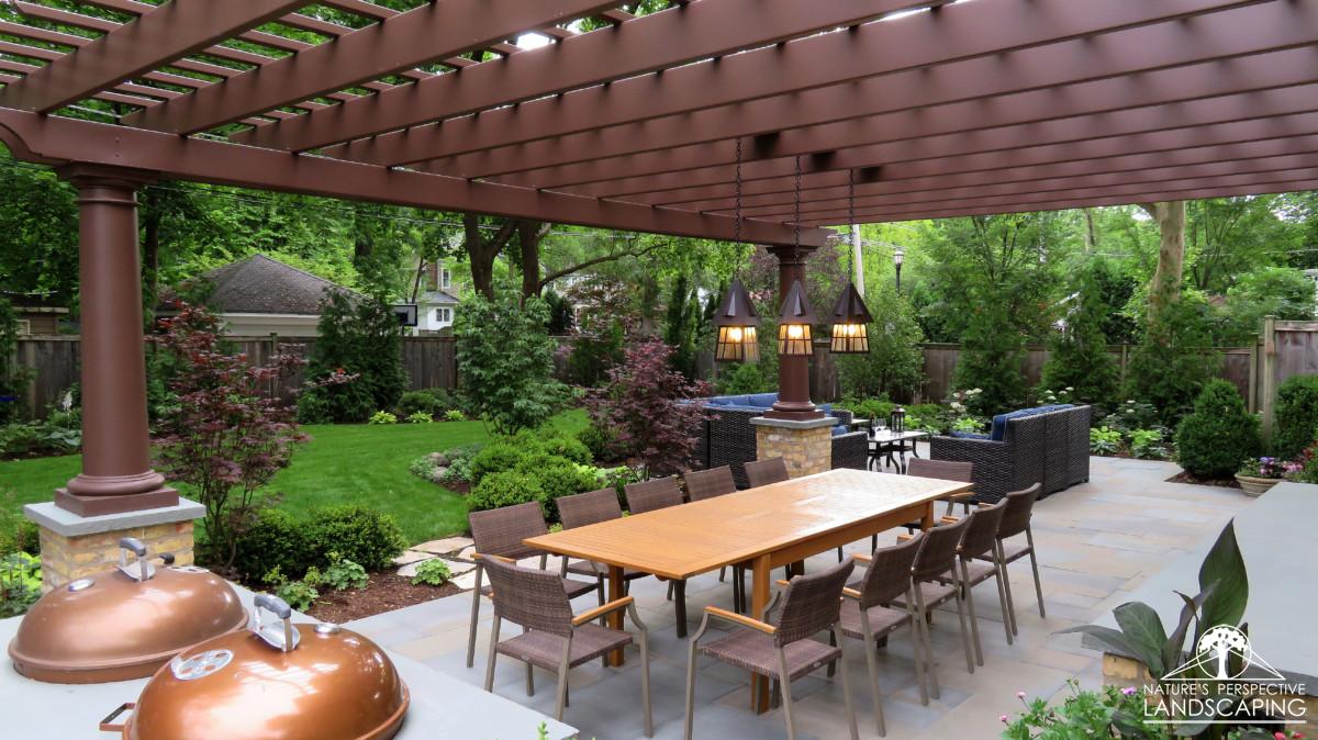 lush backyard with plantings, large fiberglass pergola and bluestone patio