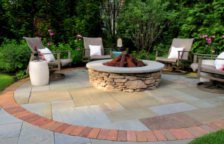 round bluestone fire pit area with fieldstone fire pit and Steelog