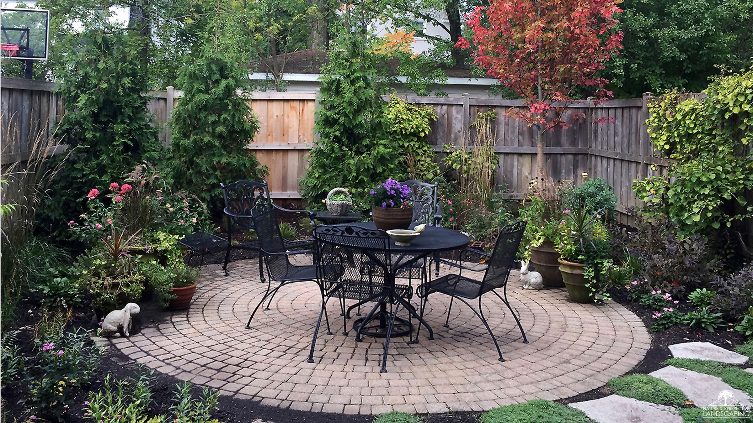 lush plantings around a round paver patio