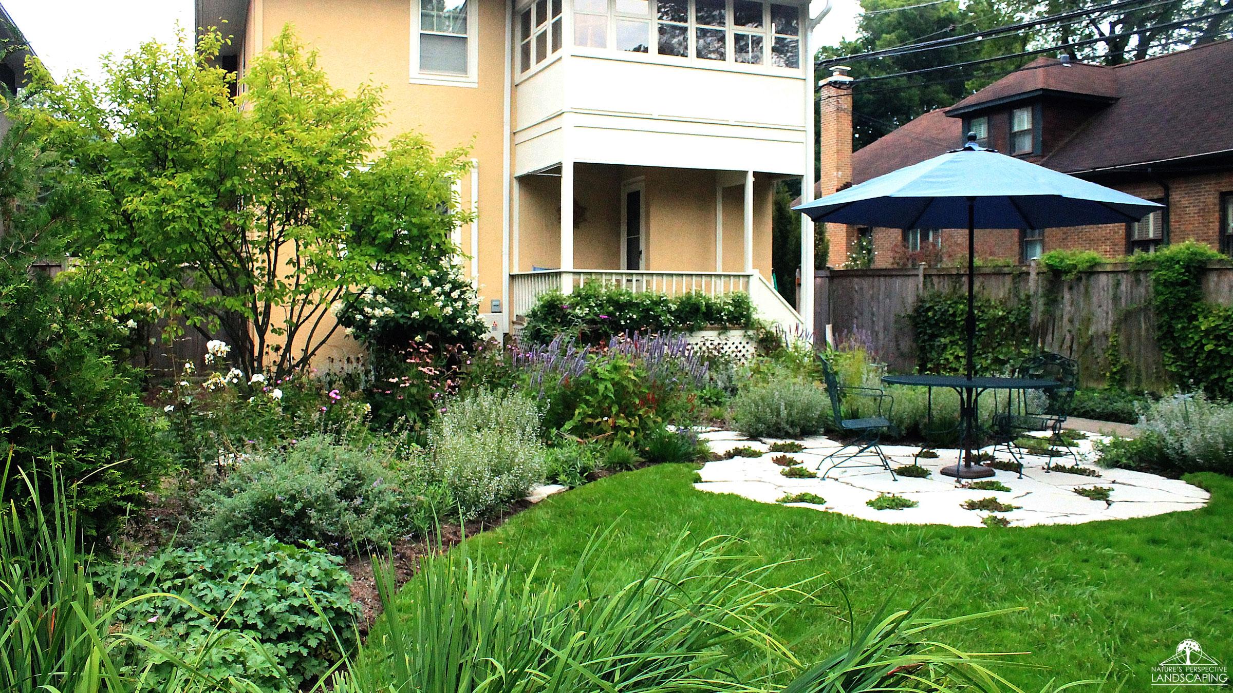 lush perennials and stone patio in backyard