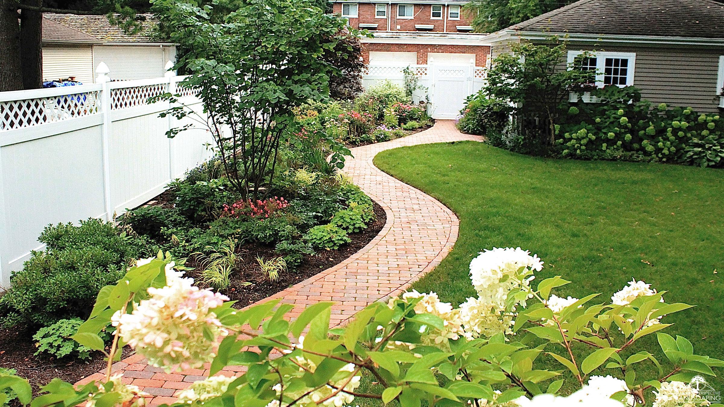 a curved brick paver path and plantings with hydrangeas